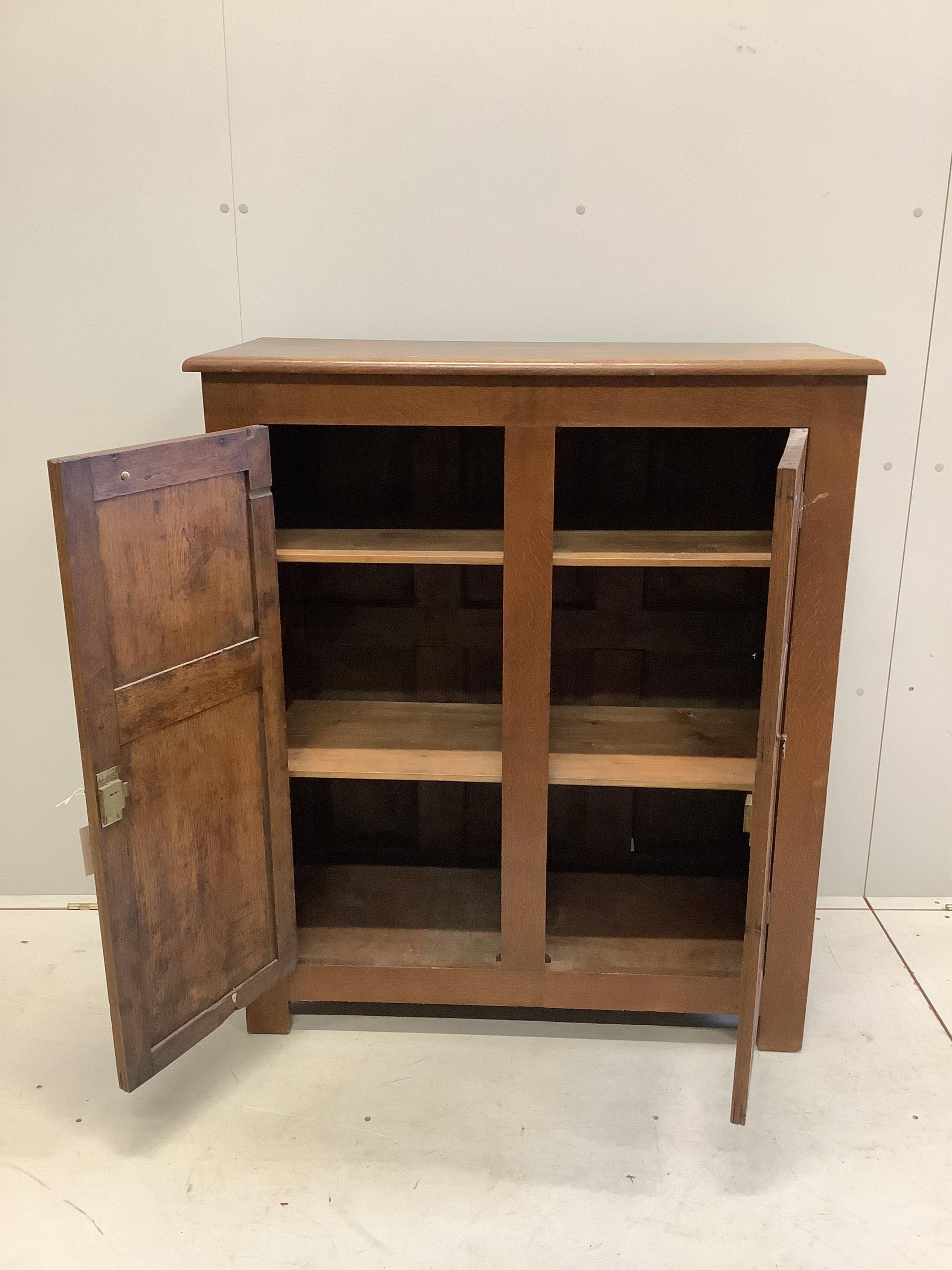 An early 20th century panelled oak two door cupboard, width 96cm, depth 42cm, height 112cm. Condition - fair, top faded, ring and spot stained.